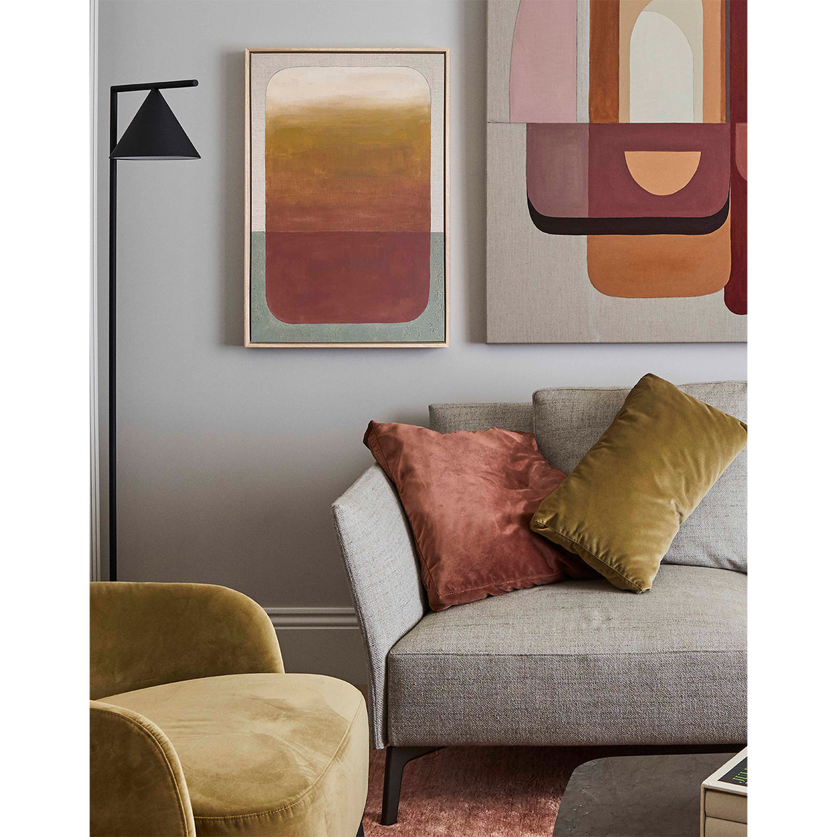Living room with a gray sofa, yellow armchair, and abstract art on the wall.