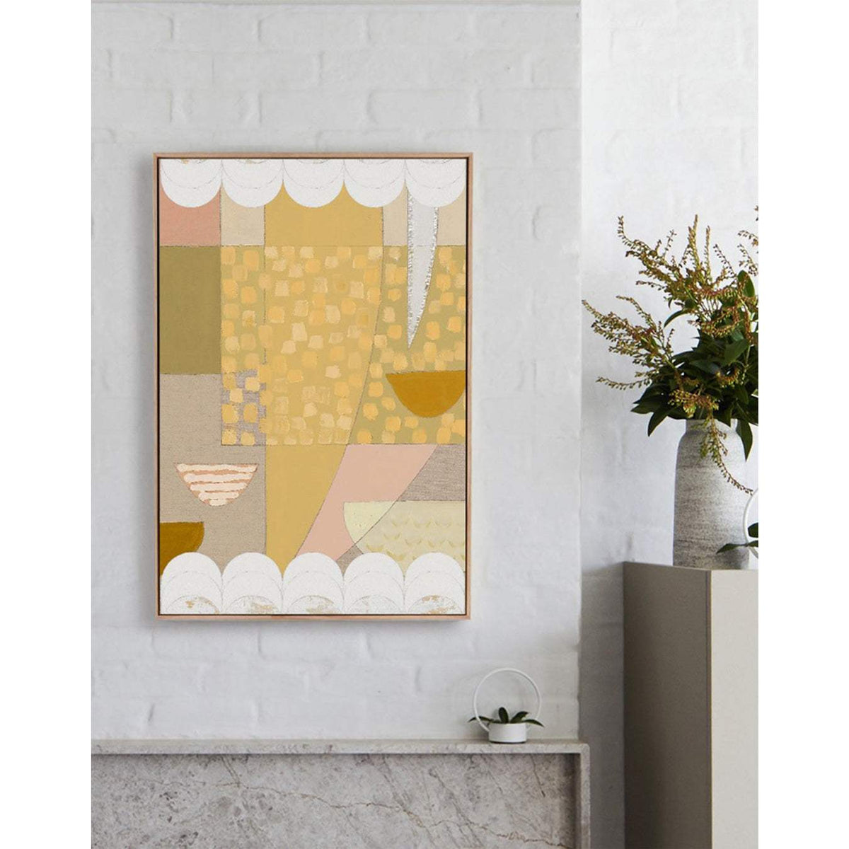 A framed abstract artwork featuring geometric shapes in orange and other colors, with white scalloped lines on a wall.