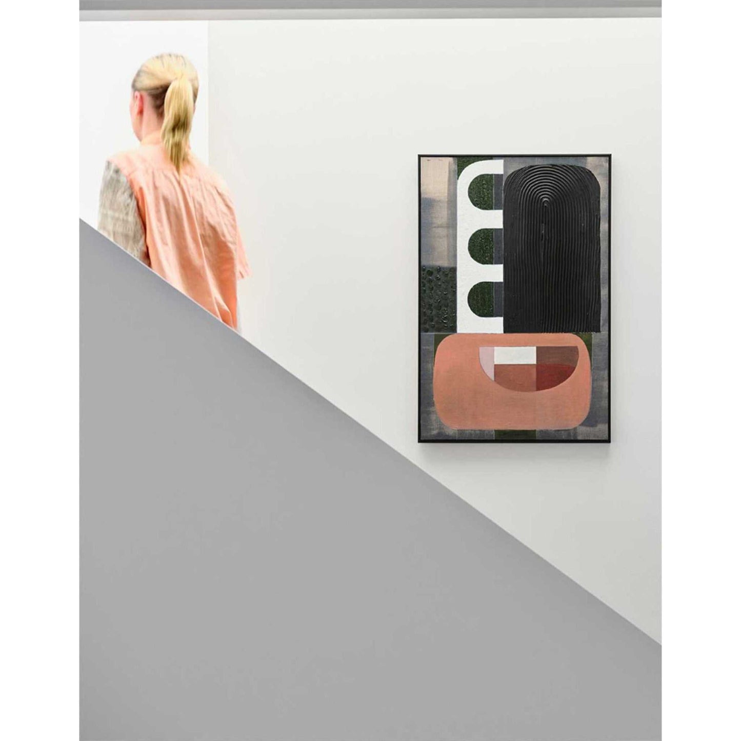 A framed giclee print featuring geometric shapes in a contrast of colors, with a person partially visible at the top of the image, looking at the artwork.