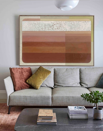 Studio Elwood “Crimson Rust Ombre” — contemporary abstract artwork in layered terracotta, blush and sand tones, framed in oak and styled above a modern sofa with warm earthy accents and minimalist décor.
