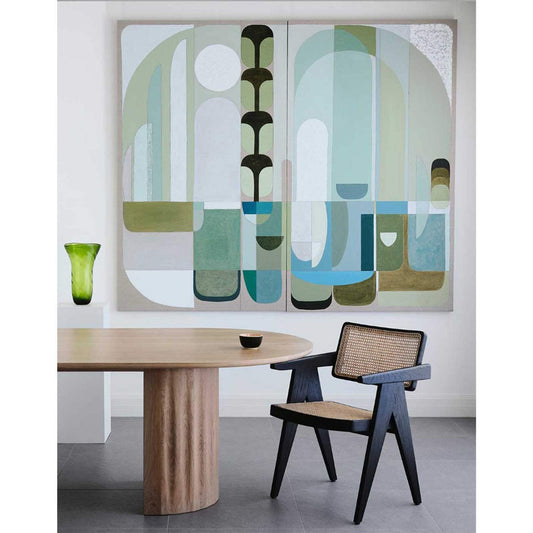 Diptych abstract wall art print featuring geometric shapes in green and blue tones, displayed above a wooden table with a vase of greenery in a modern interior setting.