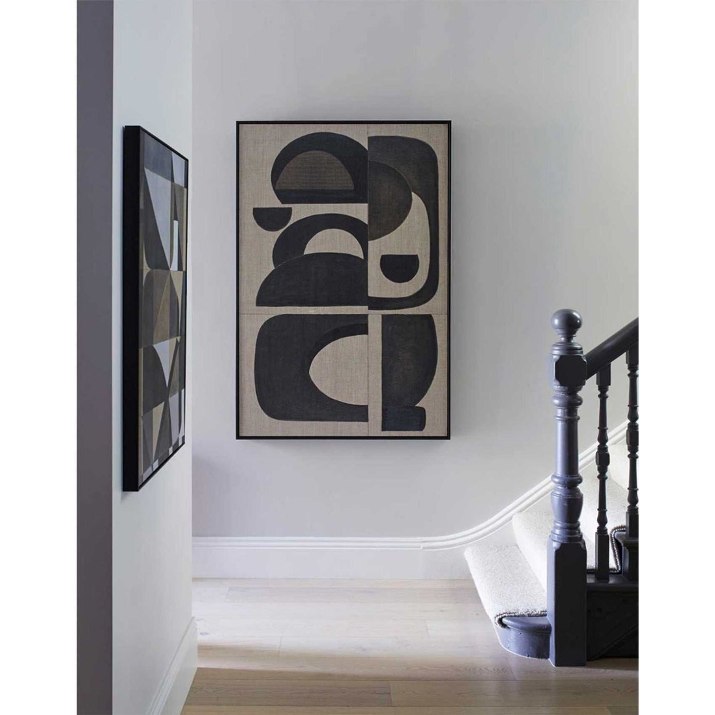 A framed abstract wall art print featuring abstract black geometric shapes on a wall in a home environment.