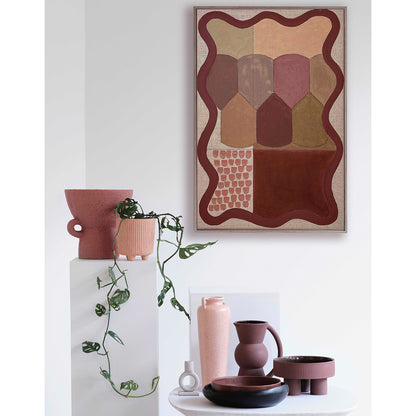 Decorative setting with a abstract art piece, vases, and plants on a white surface.