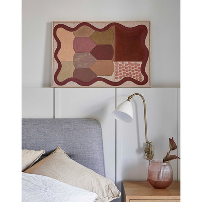 Bedroom interior with abstract art above a bed and a lamp on a nightstand.