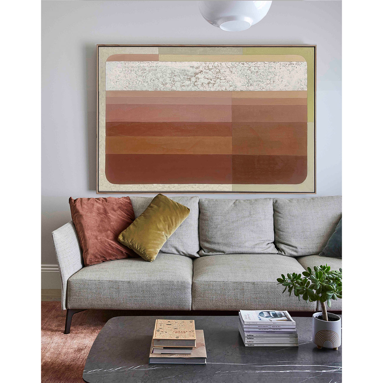 Gray sofa with colorful pillows and a abstract art piece on the wall in a living room.