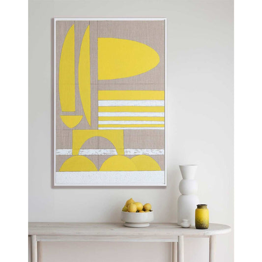 A framed Giclee print featuring a geometric yellow shape with white textural elements, displayed on a side table next to a vase with citrus fruit.